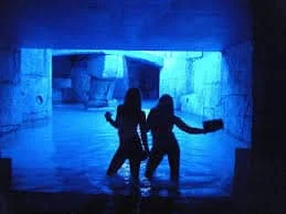 Two friends enjoying a dip in the illuminated waters of Aqua Club in Ayia Napa, captured in a vibrant cave setting.