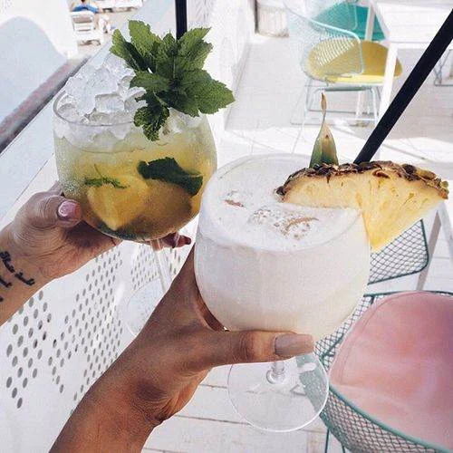 Toasting with tropical cocktails at a lively outdoor party spot during an Ibiza clubbing holiday.