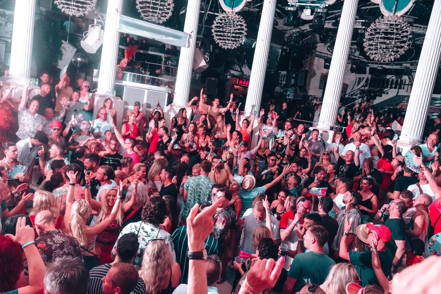 Partygoers packed into Es Paradis Ibiza, hands in the air, dancing under bright lights and soaking up pure Ibiza energy.