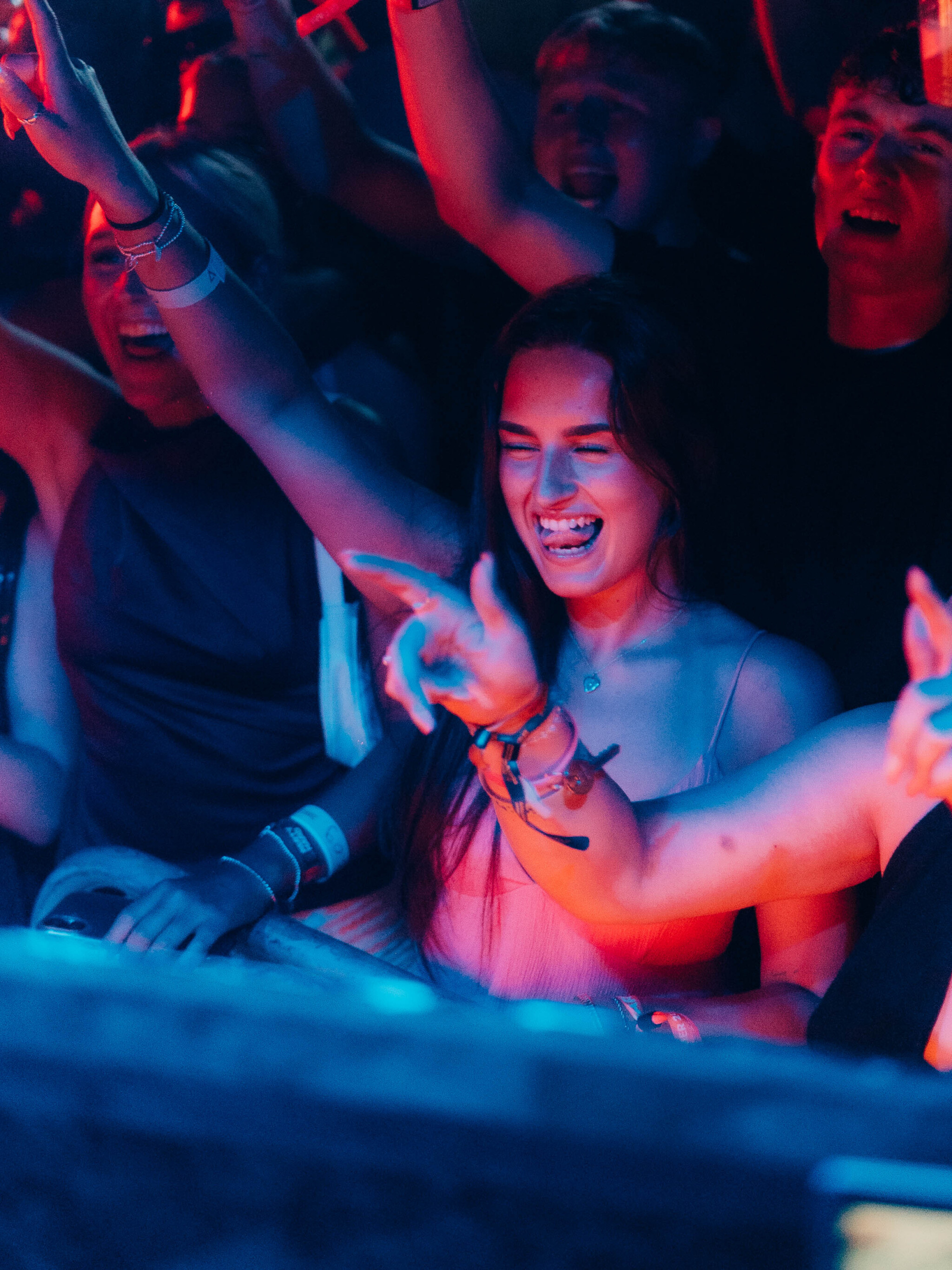 Smiling woman dances in the crowd at the House of Tech event in Ayia Napa, surrounded by friends under vibrant lights.