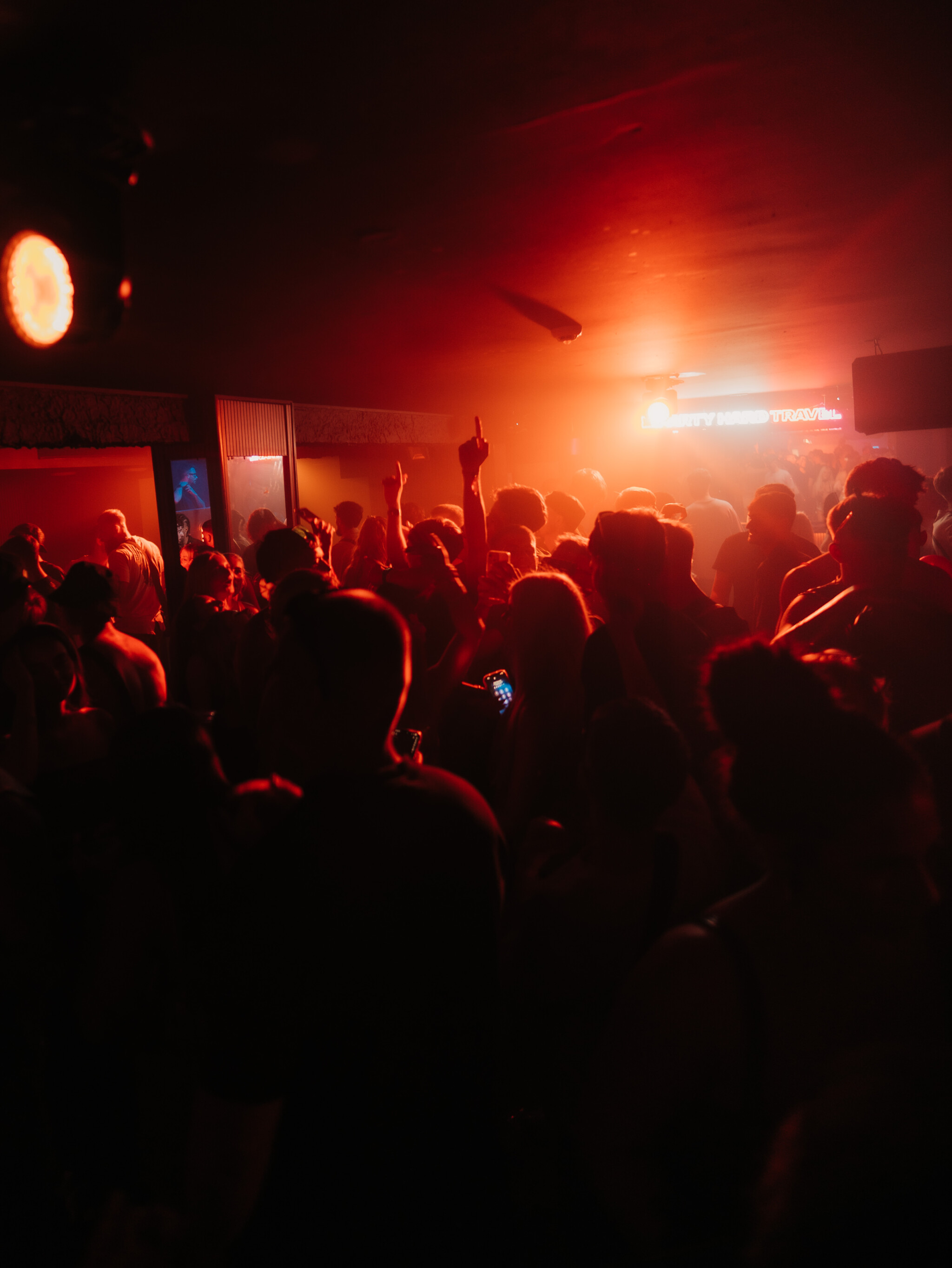 Crowd enjoying the Lovejuice Residency event in Ayia Napa under red stage lights, with people dancing and raising their hands.