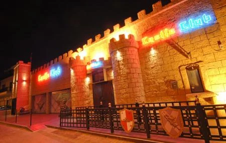 Castle Club in Ayia Napa, with a medieval stone facade and neon signage, illuminated against the night sky.