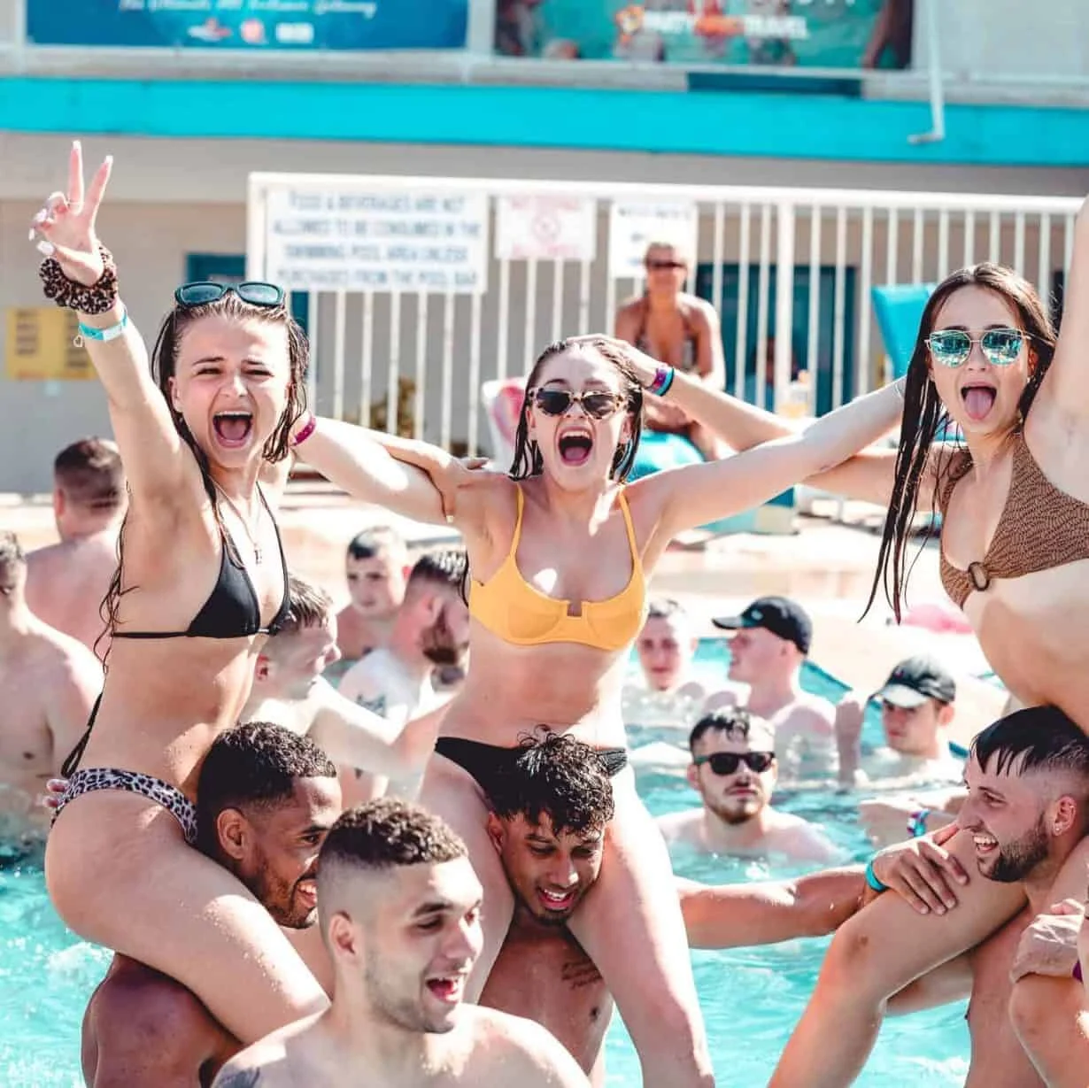 Lively pool scene at Levels Beach Bar in Ayia Napa, with friends enjoying shoulder rides and a vibrant atmosphere under clear skies.