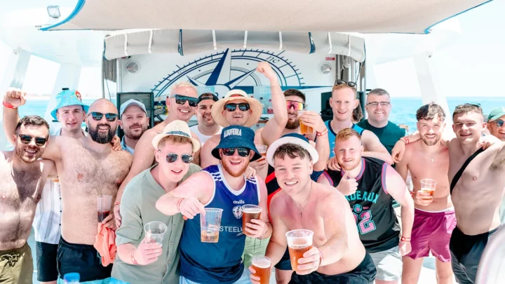 Group of lads enjoying drinks and posing for a photo on a Party Hard Travel boat party in Albufeira.