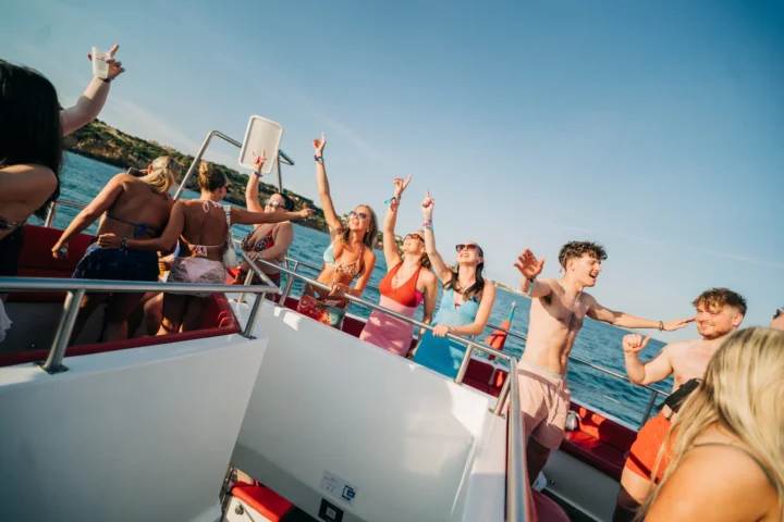 Lads and girls laughing and pointing to the sky on the deck at the Albufeira Boat Party, celebrating under the Algarve sun with ocean views.