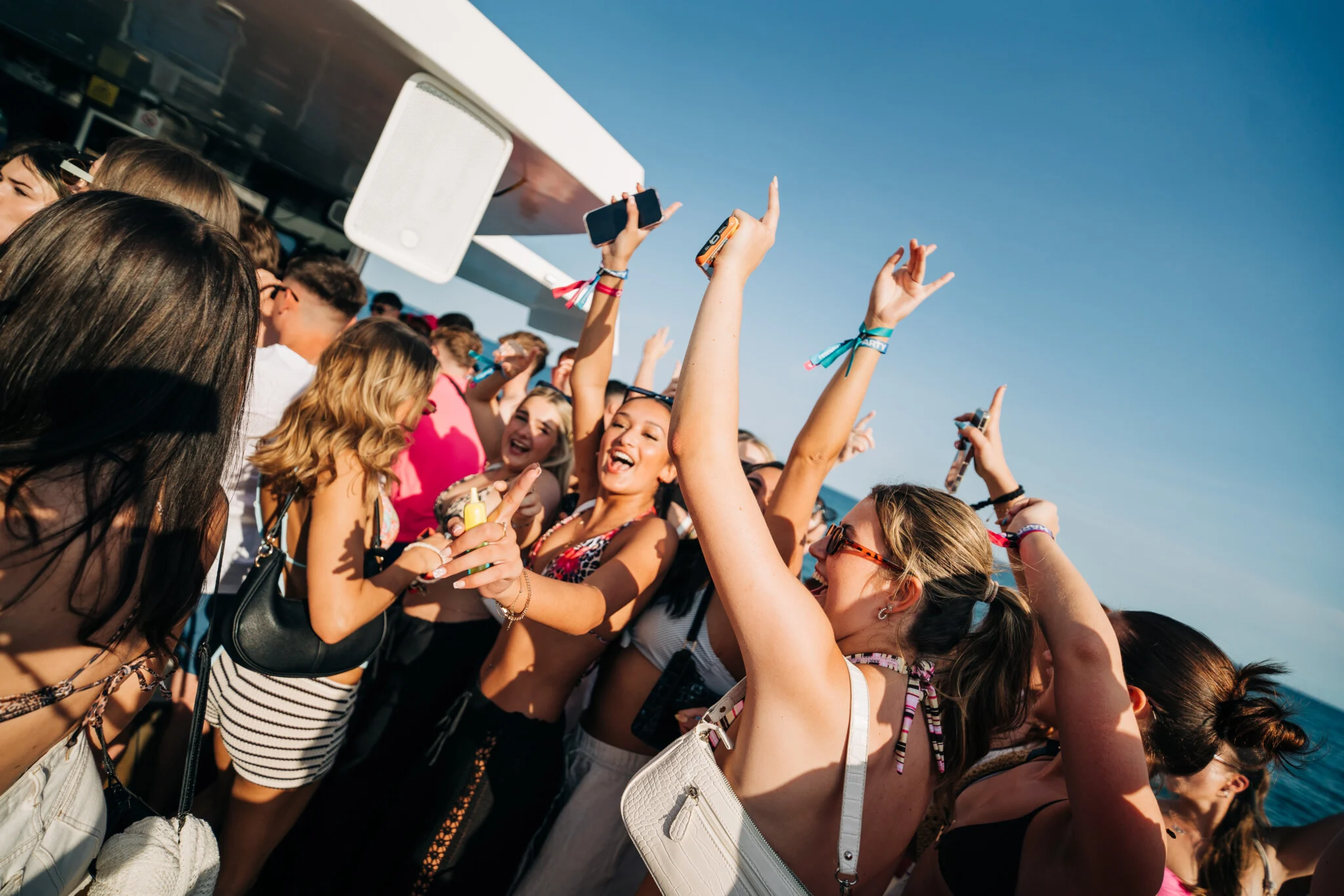 Girls dancing and celebrating with hands in the air at the Albufeira Boat Party in Albufeira, enjoying sunshine, music and the lively holiday atmosphere.