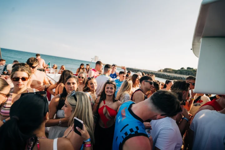 Lads and girls enjoying the Albufeira Boat Party, with music, drinks, and sunshine as they dance together on deck with Algarve sea views.