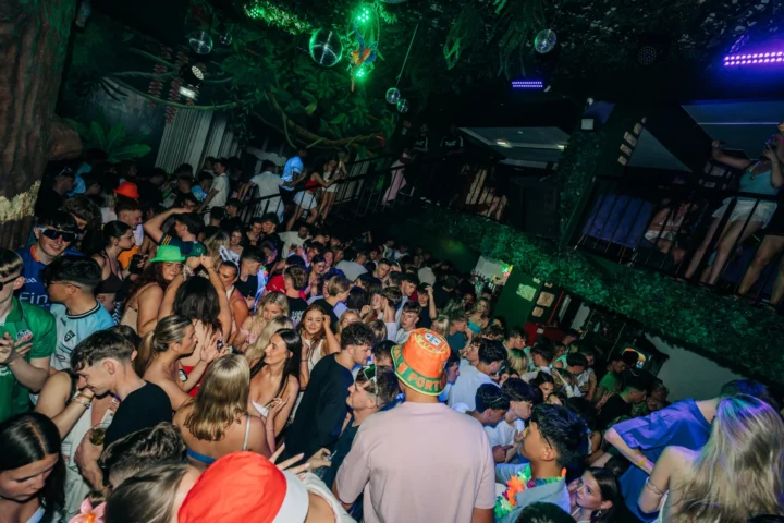 Packed dancefloor at Club Tropicana Albufeira as partygoers celebrate under neon lights and jungle-themed décor.