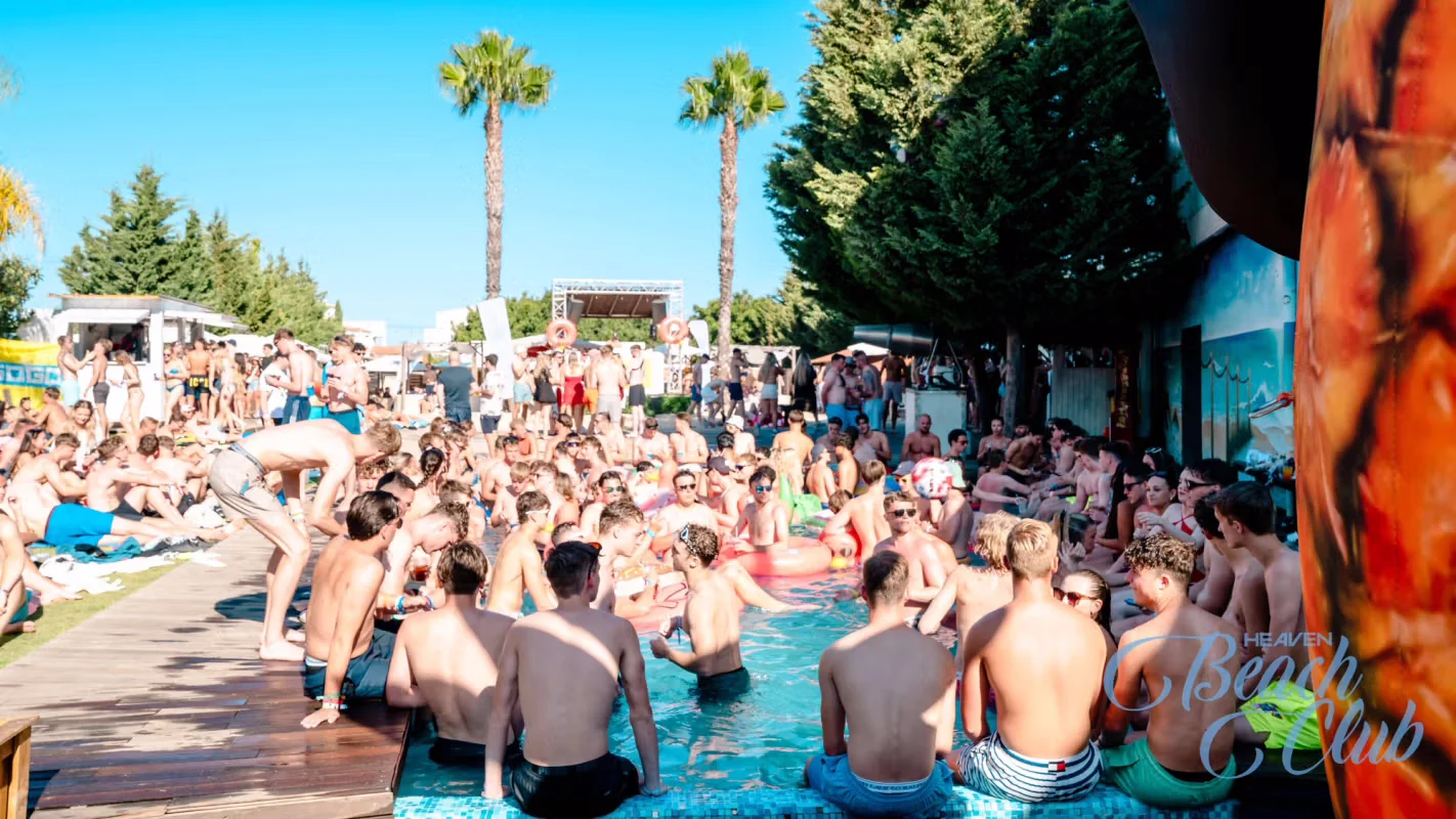 Crowds partying in the sun at an Albufeira pool party with drinks, DJs, and inflatable fun at Heaven Beach Club.