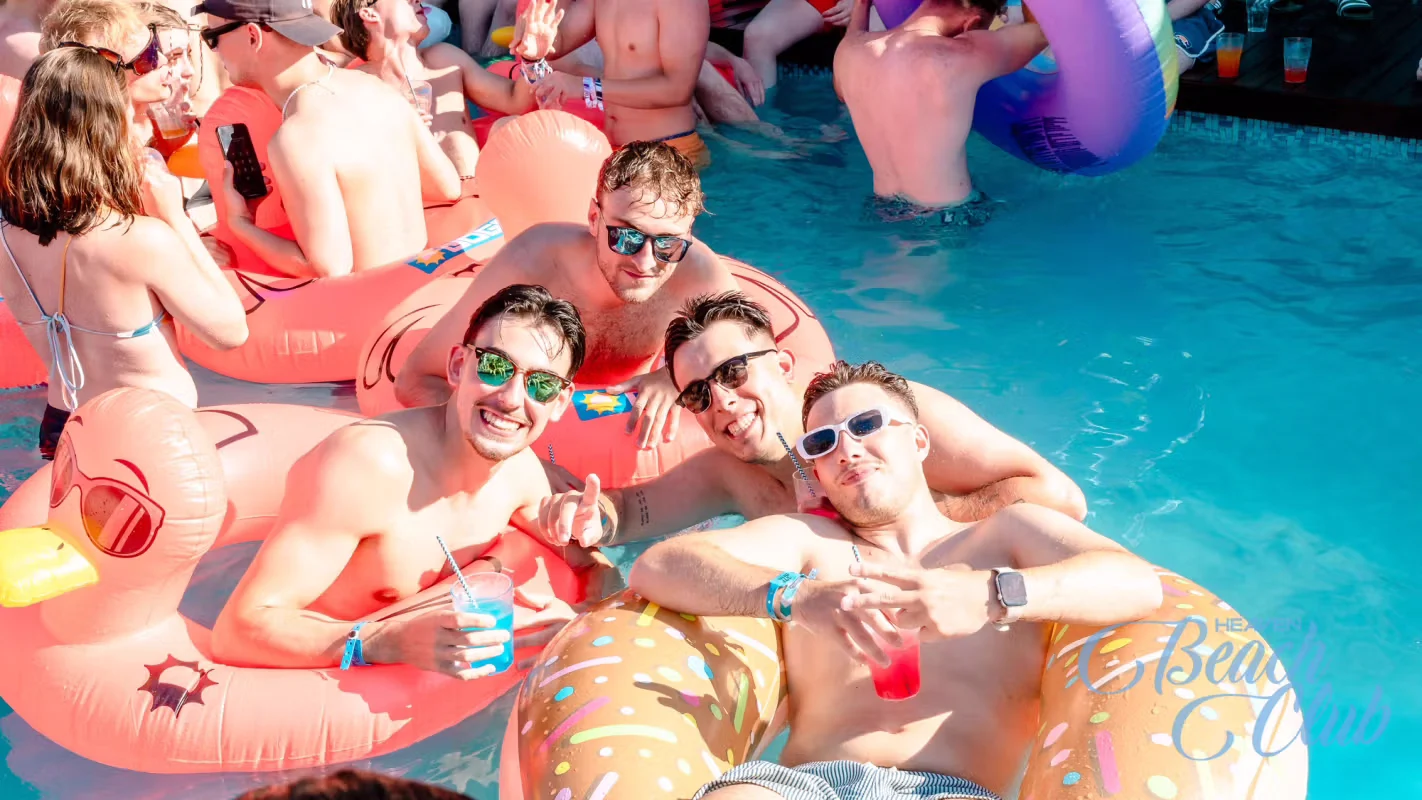 Group of lads on inflatables with drinks, enjoying the pool party vibes at Heaven Beach Club in Albufeira.
