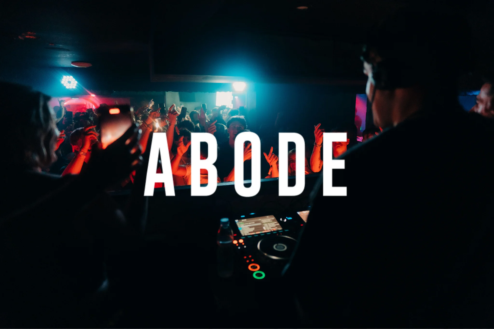 Crowd partying at Ayia Napa Abode event with DJs performing in a packed nightclub atmosphere under red and blue lights