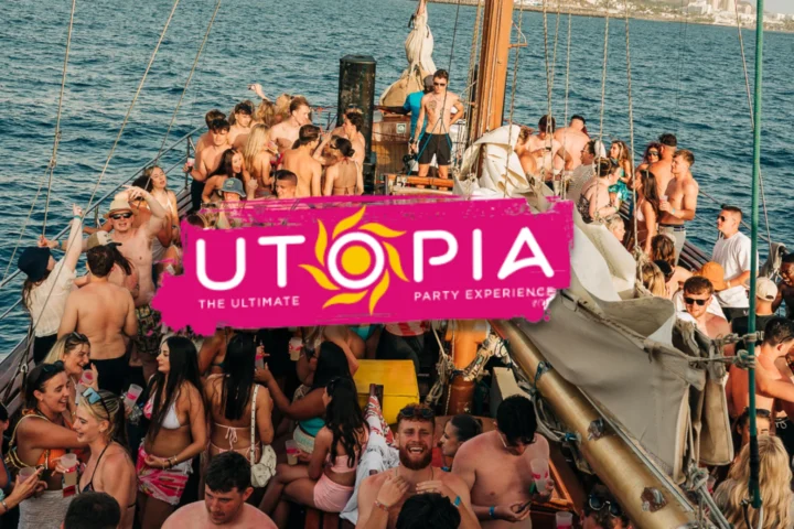 Crowded Tenerife boat party with lads and girls dancing on deck, UTOPIA banner centre stage and full daytime chaos