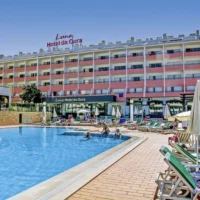 View of Luna Hotel da Oura in Albufeira with outdoor pool, sun loungers, and guests relaxing under clear blue skies.