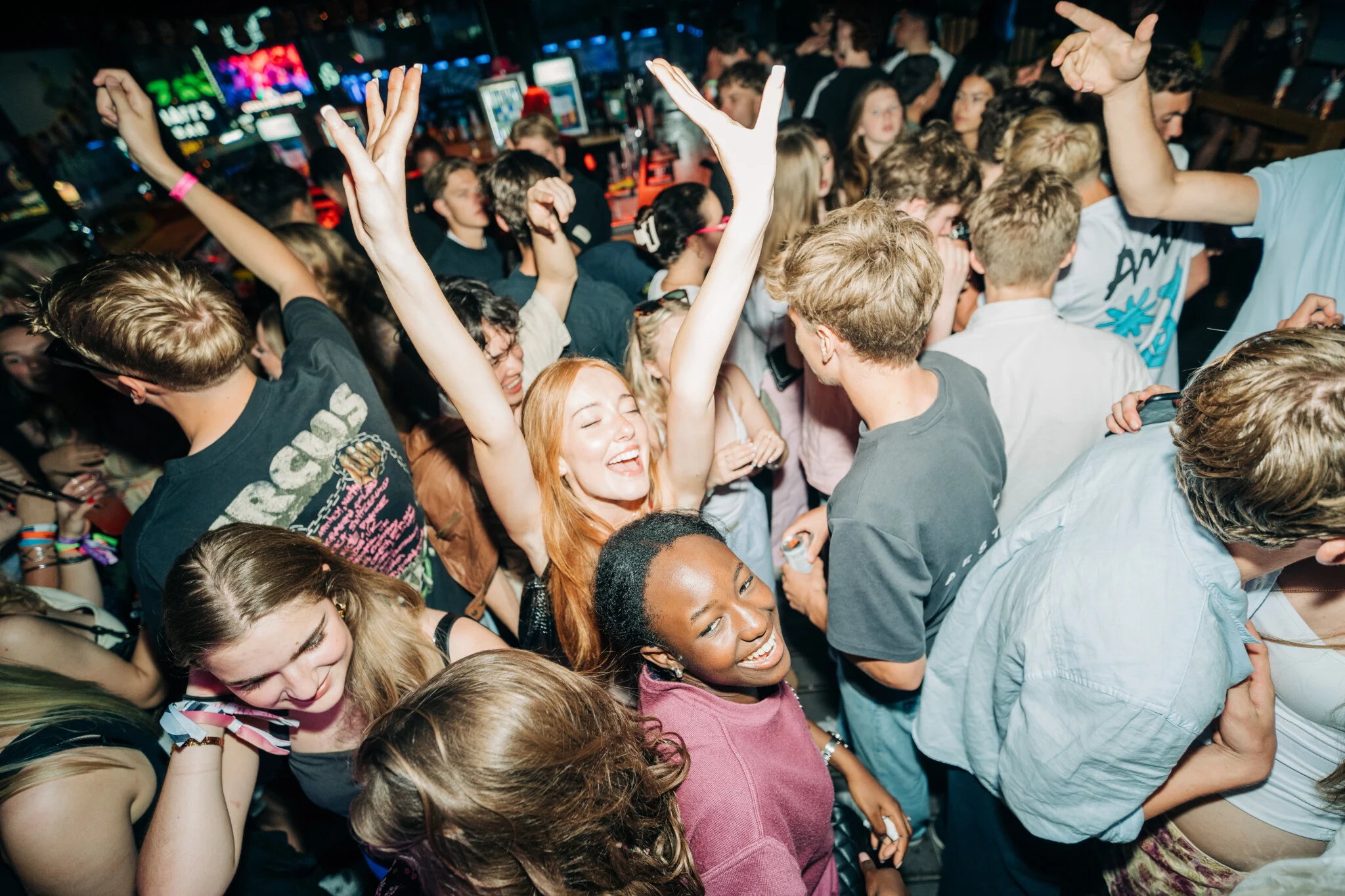 Party crowd in an Albufeira club, dancing with hands in the air, big smiles and nonstop energy on the packed dancefloor.