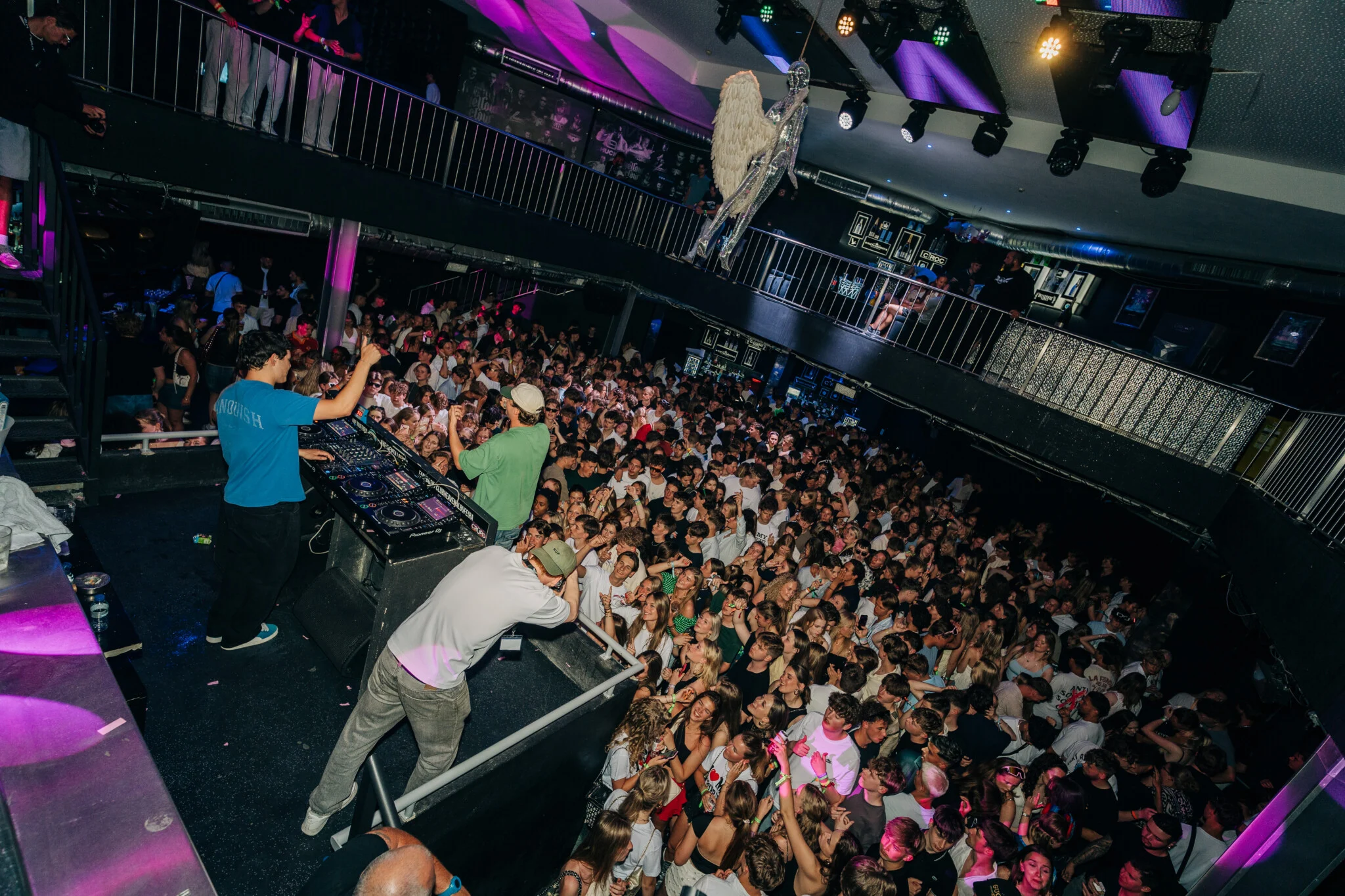 DJ hyping the crowd at a packed Albufeira event, lights flashing, music pumping and everyone partying hard.