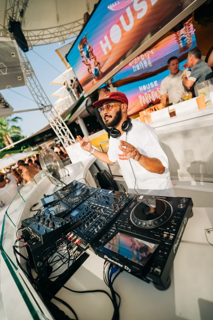 DJ performing at a Ibiza pool party, hyping the crowd with house beats under the sun at House of Paradise.