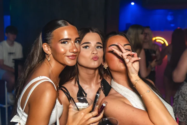 Girls posing on a packed Barcelona club night, drinks in hand and buzzing with party energy under the neon lights.