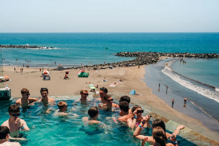 Lads and girls partying in a Tenerife infinity pool with drinks, sea views and beach vibes rolling all day long