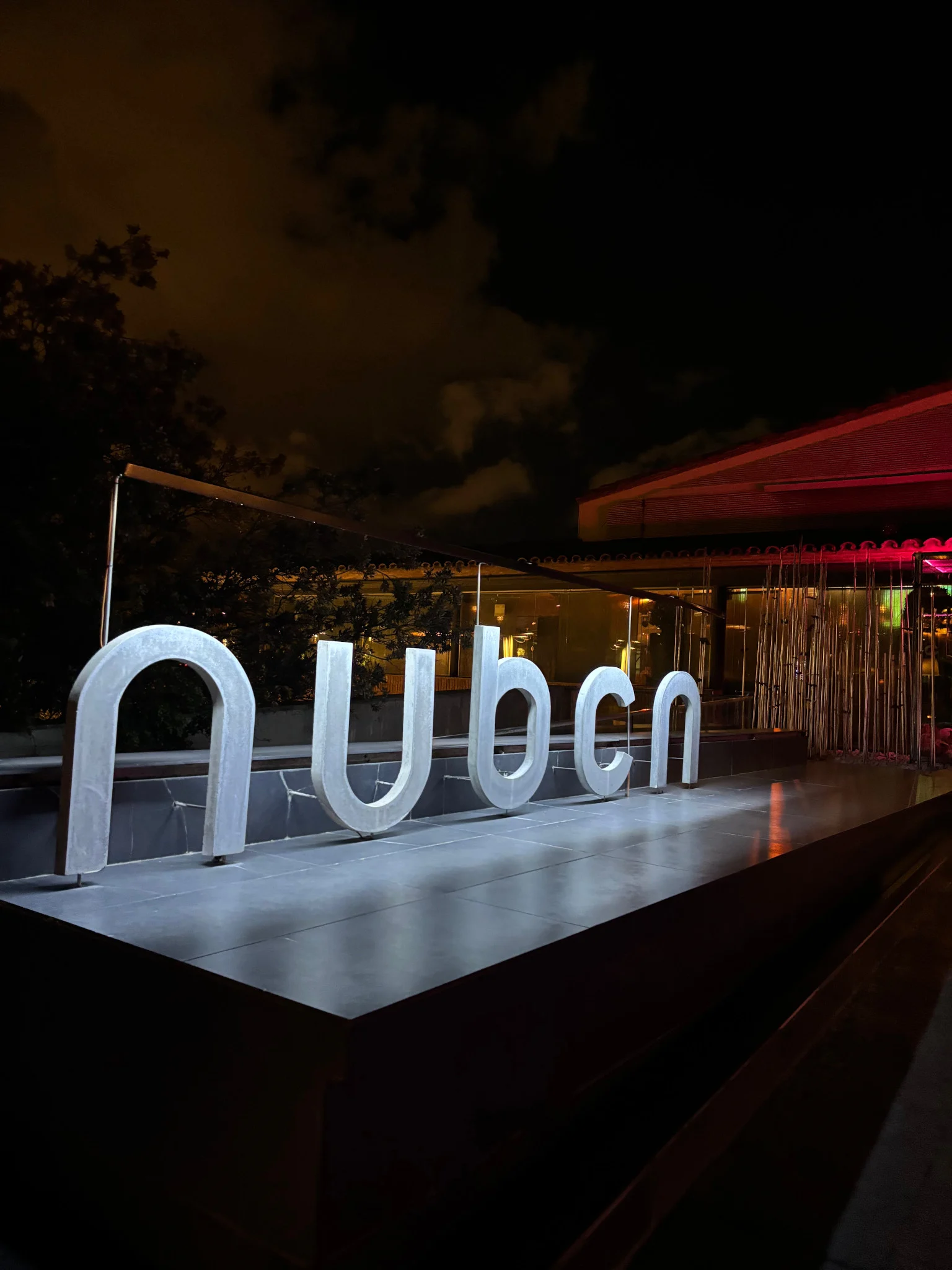 Lit-up NUBCN sign glowing at night in Barcelona, marking the entrance to a stylish spot before the night kicks off.