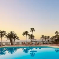Sol Tenerife Hotel pool at sunset, palm-lined terrace and sea views setting the scene for pre-party drinks and warm nights